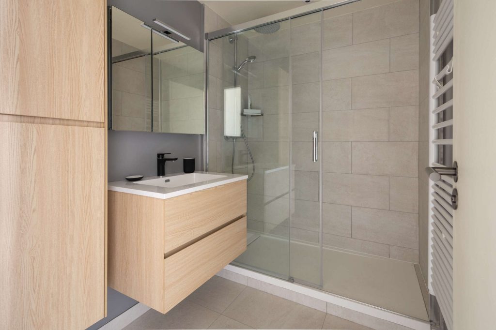 Salle de bain rénovée avec douche à l’italienne, faïence murale et équipements premium.